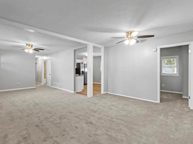 unfurnished living room with light carpet and ceiling fan