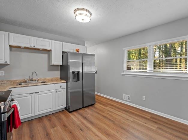 kitchen with white cabinets, appliances with stainless steel finishes, light wood-type flooring, and sink