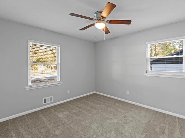 carpeted spare room with plenty of natural light and ceiling fan