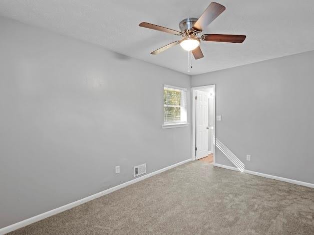 spare room with ceiling fan and light colored carpet