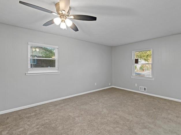 empty room featuring light carpet, a wealth of natural light, and ceiling fan