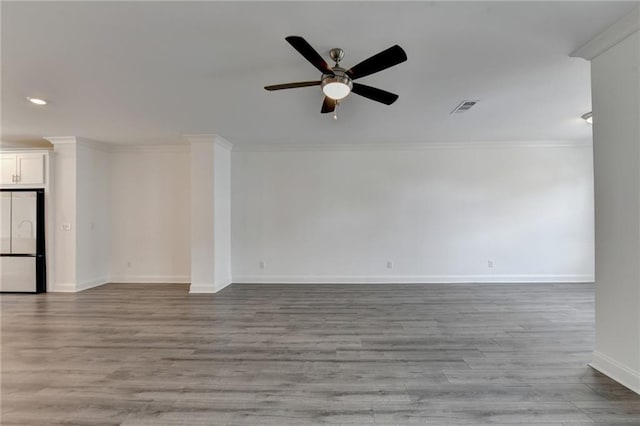 spare room with visible vents, wood finished floors, a ceiling fan, and ornamental molding