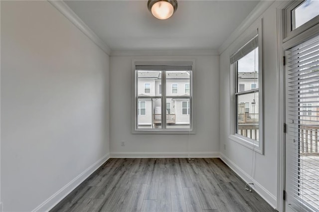 empty room featuring crown molding, baseboards, and wood finished floors