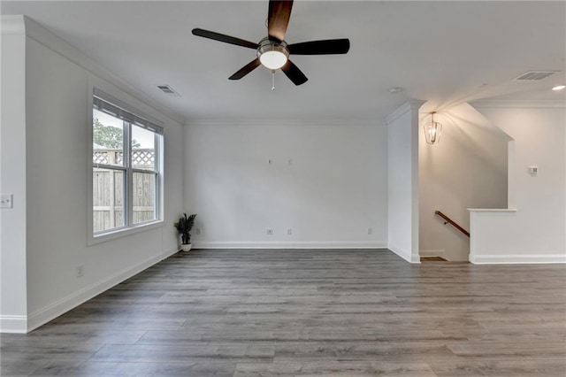 unfurnished living room featuring visible vents, crown molding, baseboards, and wood finished floors