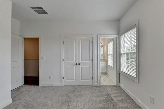 unfurnished bedroom featuring baseboards, visible vents, a closet, ensuite bathroom, and carpet flooring