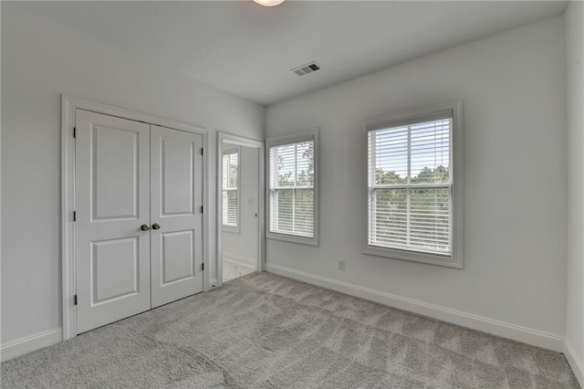 unfurnished bedroom with a closet, visible vents, baseboards, and carpet