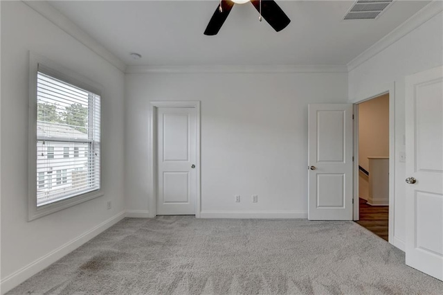 unfurnished bedroom with carpet, visible vents, baseboards, ceiling fan, and crown molding