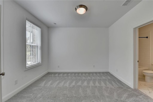 unfurnished bedroom with visible vents, carpet flooring, ensuite bathroom, and baseboards