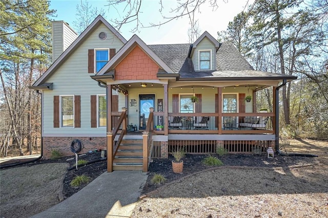 view of front of home with covered porch, roof with shingles, and a chimney