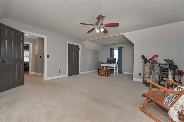 interior space with lofted ceiling, light colored carpet, ceiling fan, a textured ceiling, and baseboards