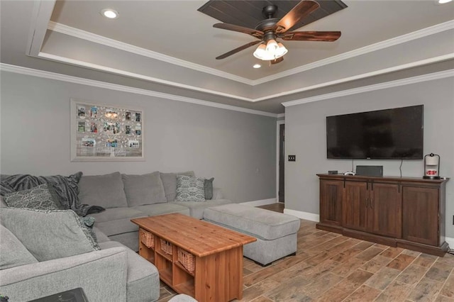 living room with baseboards, light wood-style flooring, ceiling fan, ornamental molding, and a tray ceiling