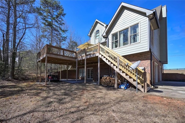 exterior space with brick siding, stairway, an attached garage, a deck, and driveway