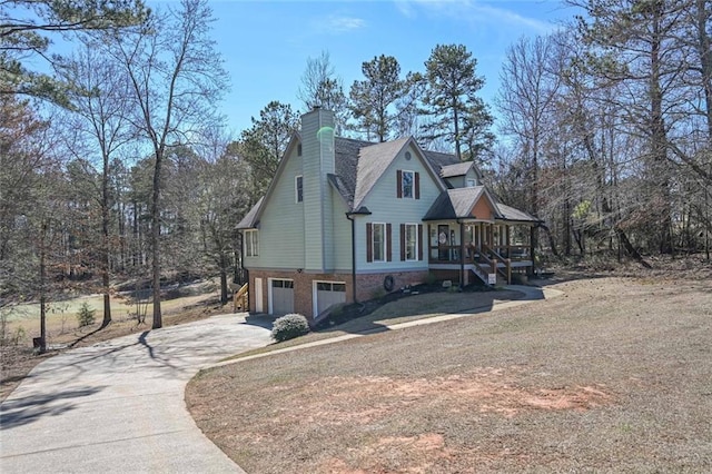 view of side of home featuring brick siding, a chimney, a porch, concrete driveway, and a garage