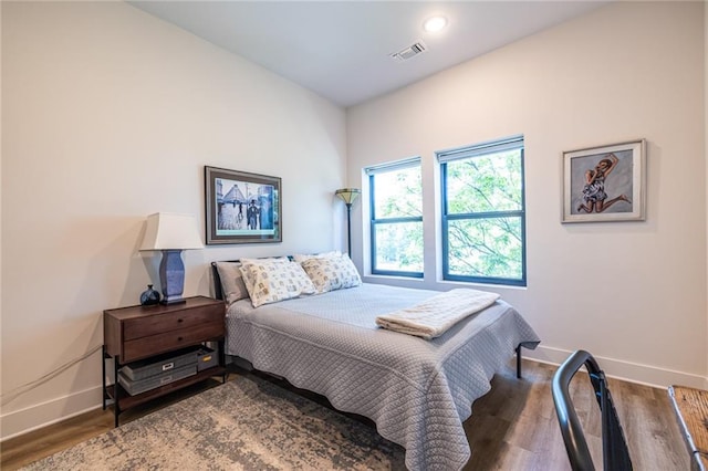 bedroom featuring baseboards, wood finished floors, and visible vents