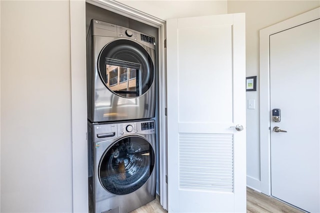 laundry room featuring laundry area, stacked washer / dryer, and light wood-style flooring