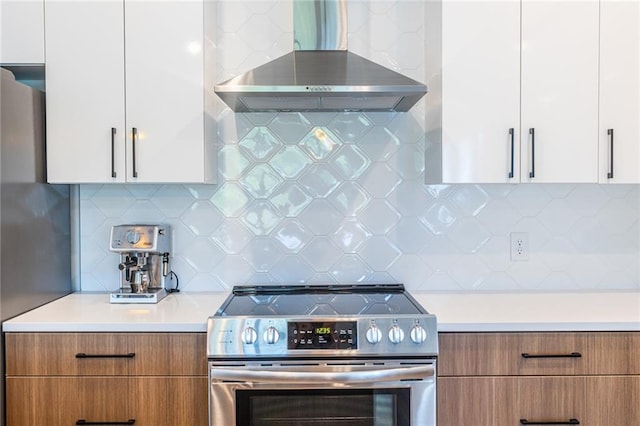 kitchen featuring modern cabinets, light countertops, wall chimney exhaust hood, brown cabinets, and appliances with stainless steel finishes