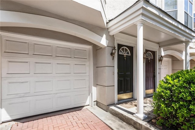 property entrance with a garage, decorative driveway, and stucco siding