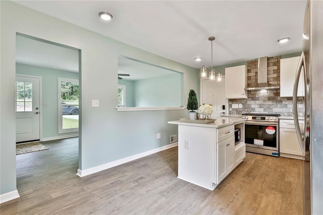 191 Pine St NE, Fairburn, GA 30213 - kitchen featuring wall chimney range hood, appliances with stainless steel finishes, white cabinets, tasteful backsplash, and light wood finished floors