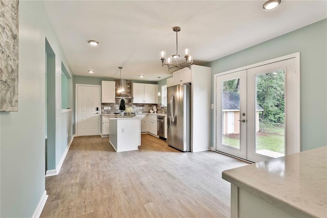 191 Pine St NE, Fairburn, GA 30213 - kitchen with stainless steel appliances, wall chimney exhaust hood, a chandelier, light wood finished floors, and a kitchen island