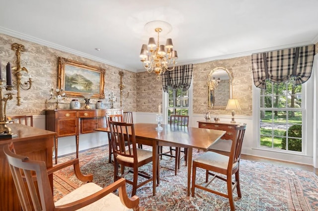 dining room featuring a chandelier, a wainscoted wall, crown molding, wallpapered walls, and wood finished floors