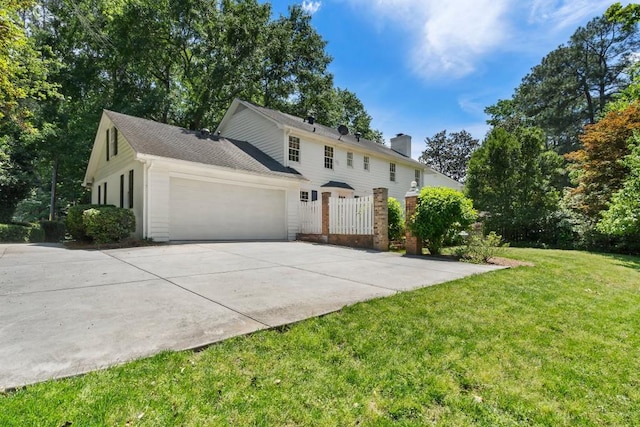 view of front of property featuring a front lawn, a garage, driveway, and a chimney