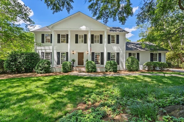 neoclassical / greek revival house with a front yard and a shingled roof