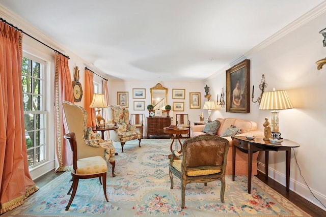 sitting room featuring baseboards, wood finished floors, and crown molding
