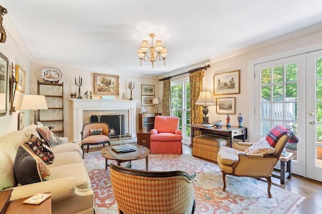 living room with a chandelier, crown molding, wood finished floors, french doors, and a fireplace with raised hearth