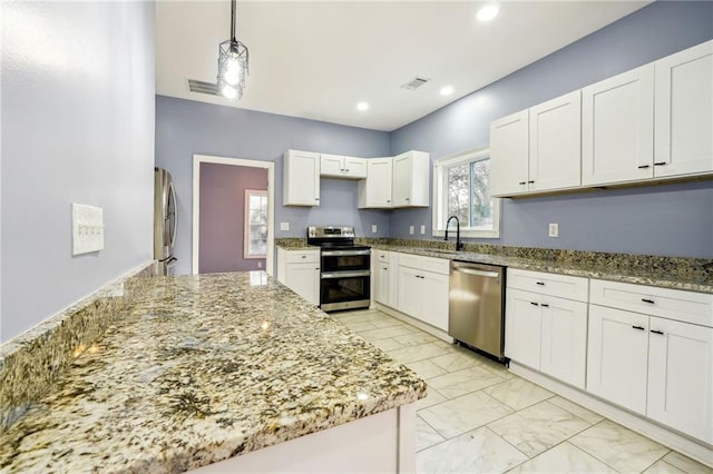 kitchen featuring white cabinetry, stainless steel appliances, light stone countertops, pendant lighting, and sink