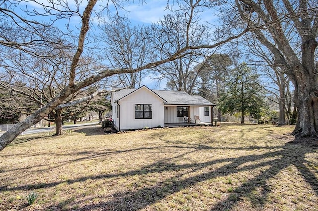 view of front facade with covered porch, board and batten siding, and a front yard