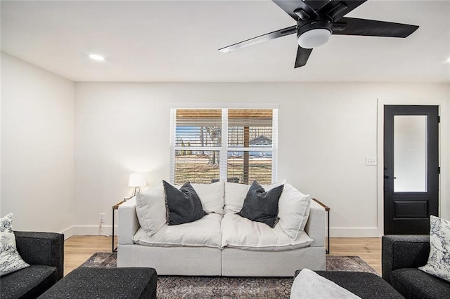 living room featuring baseboards, a ceiling fan, and light wood-style floors