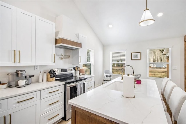 kitchen featuring light stone counters, lofted ceiling, white cabinetry, an island with sink, and stainless steel electric range