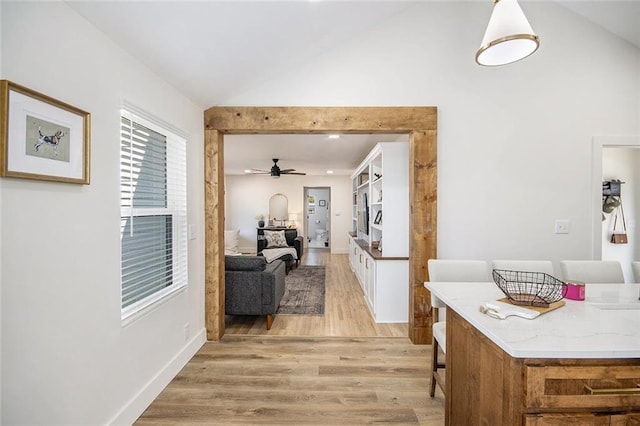 hallway with vaulted ceiling, light wood finished floors, and baseboards