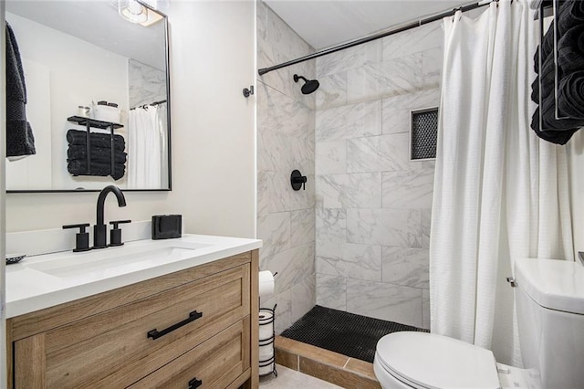 bathroom with toilet, tiled shower, and vanity