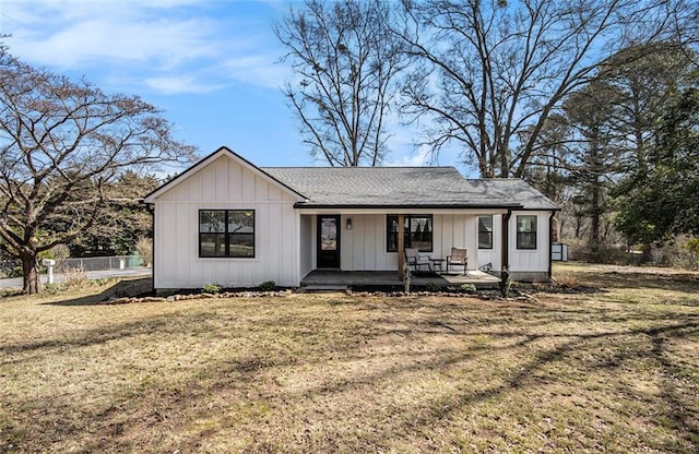 view of front of property with covered porch, fence, board and batten siding, and a front yard