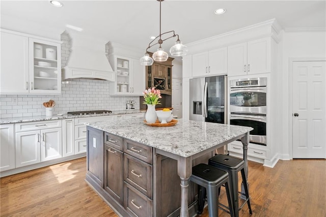6219 Creekstone Path, Cumming, GA 30041 - kitchen with stainless steel appliances, custom exhaust hood, a kitchen bar, white cabinetry, and recessed lighting