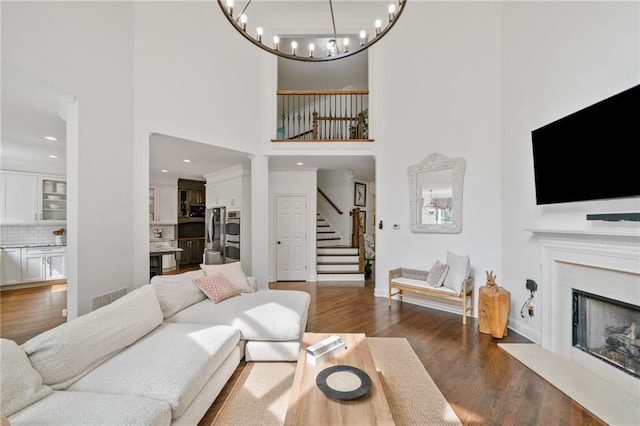 6219 Creekstone Path, Cumming, GA 30041 - living area featuring stairs, a towering ceiling, dark wood-style flooring, a premium fireplace, and a chandelier