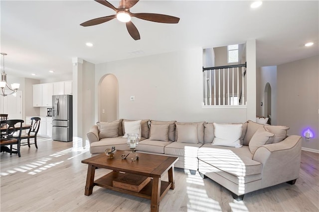 living area with recessed lighting, ceiling fan with notable chandelier, arched walkways, and light wood-type flooring