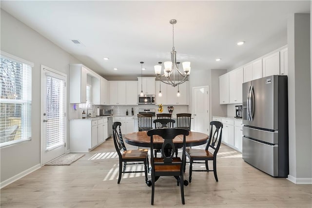 dining area with visible vents, baseboards, light wood-style floors, and an inviting chandelier