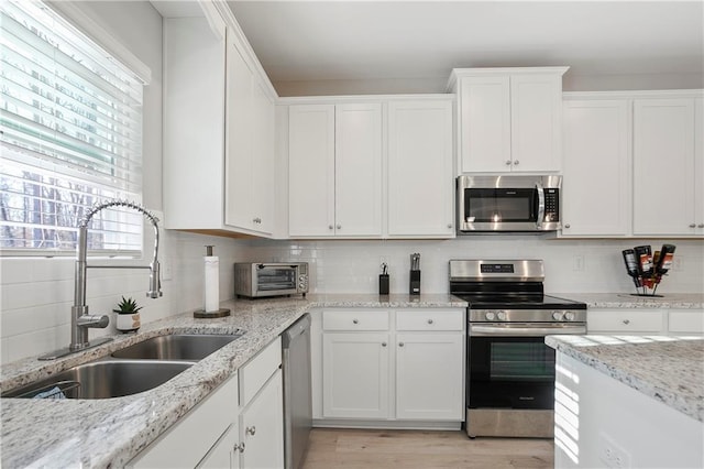 kitchen with a sink, white cabinetry, appliances with stainless steel finishes, a toaster, and decorative backsplash