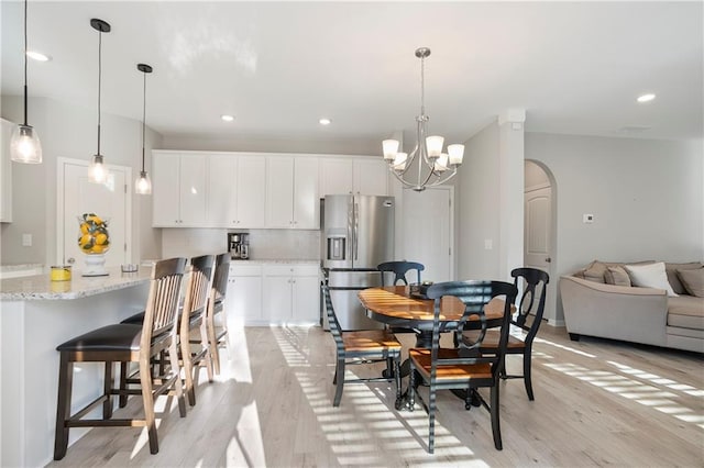 dining area featuring recessed lighting, light wood-style flooring, arched walkways, and a chandelier