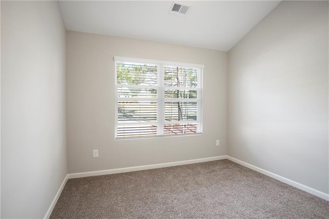 spare room with visible vents, baseboards, carpet, and vaulted ceiling