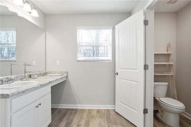 bathroom with a healthy amount of sunlight, toilet, and wood finished floors