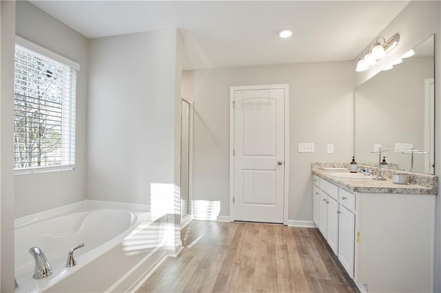 bathroom with baseboards, a garden tub, wood finished floors, and vanity