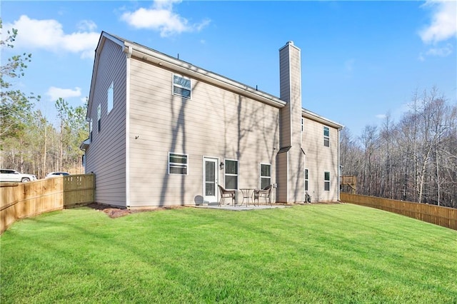 back of house with a yard, a fenced backyard, and a chimney