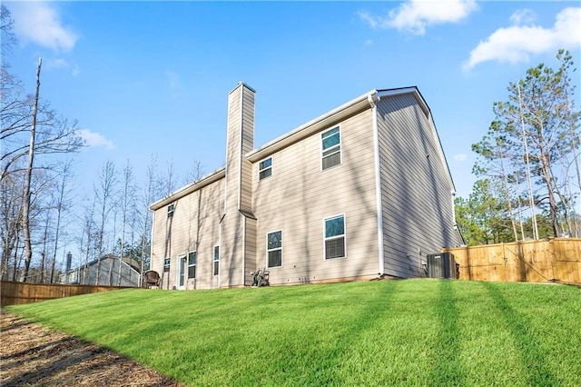 back of property featuring a yard, fence, and a chimney