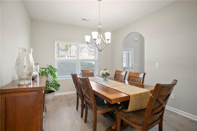 dining room with a chandelier, visible vents, arched walkways, and light wood-style floors