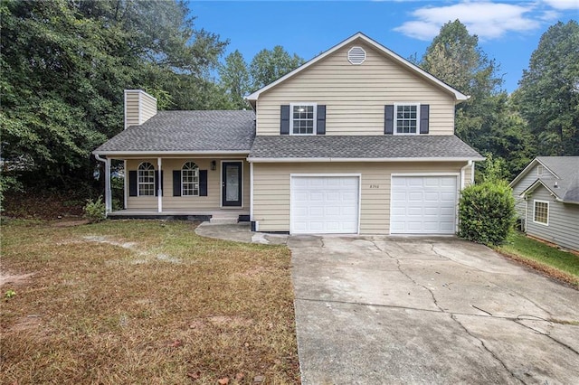 split level home featuring a chimney, concrete driveway, covered porch, a front yard, and a garage