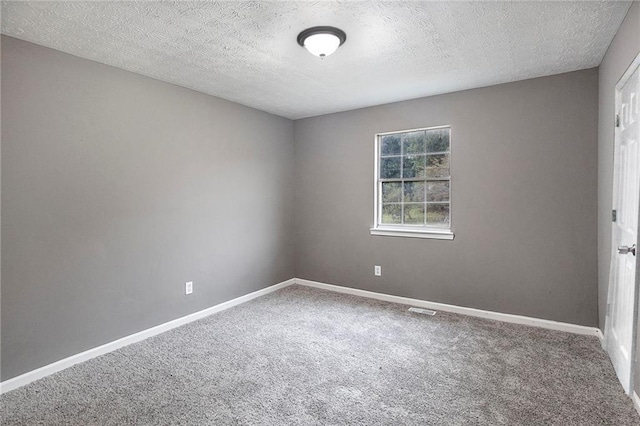 carpeted empty room featuring a textured ceiling and baseboards