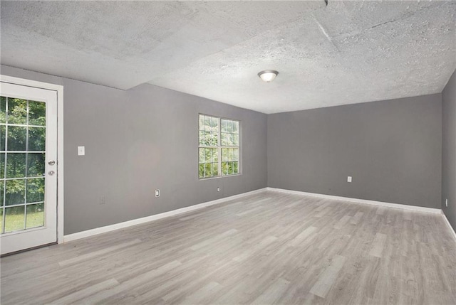 unfurnished room featuring light wood-style flooring, baseboards, and a textured ceiling